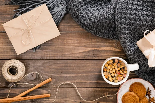 Yün ekose, zanaat kağıt zarf, ip, tarçın çubukları, bitkisel çay bardağı, hediye kutusu ile Sonbahar veya kış flatlay kompozisyon. Rahat ev, hygge kavramı. Düz döşeme, üst görünüm, genel merkez.