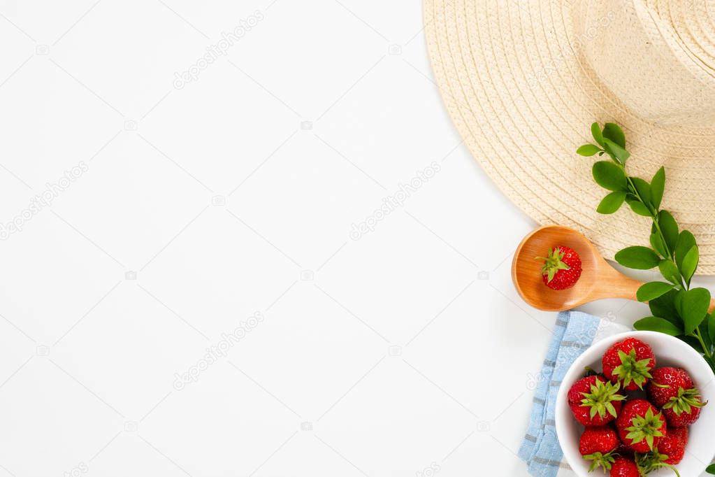Summer morning breakfast concept with strawberry in bowl, straw hat, barberry branches on white background. Flat lay, top view, overhead.