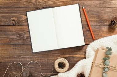 Sonbahar flatlay kompozisyon. Boş sayfaları, kırmızı kalem, ip, ahşap arka plan üzerinde hediye kutusu ile kitap üst görünümü. Sonbahar hygge tarzı masa veya kış tatili konsepti.