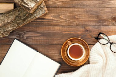 Sonbahar kompozisyonu. Bir fincan çay, kadın moda atkısı, gözlük, ahşap arka plan üzerinde odun. Düz döşeme, üst görünüm, kopyalama alanı. İskandinav hygge kavramı.