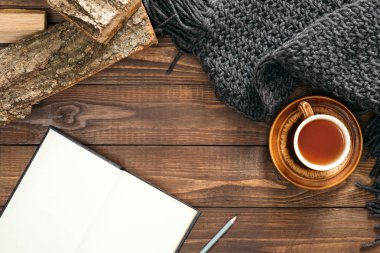 Sonbahar kompozisyonu. Boş sayfaları, çay fincan, kadın moda kazak, ahşap arka plan üzerinde yakacak odun ile kitap. Düz döşeme, üst görünüm, kopyalama alanı. İskandinav hygge kavramı.