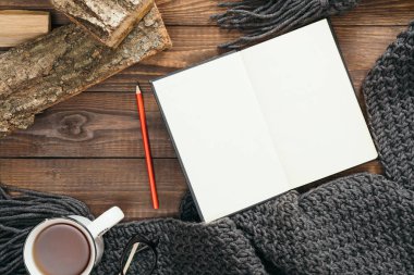 Kitap, kahve fincanı, moda örme eşarp, ahşap arka plan üzerinde yakacak odun ile Hygge tarzı flatlay kompozisyon. Düz yatıyordu, üstten bak, tepede. Rahat sonbahar ev masası masası