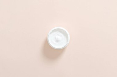 Pastel pembe arka plan üzerinde nemlendirici el kremi ile Kavanoz. Cilt bakımı kozmetik kavramı. Minimal düz döşeme stili kompozisyon, üst görünüm, genel merkez.