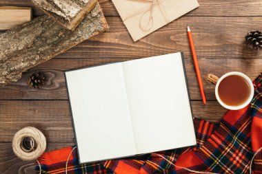 Hygge tarzı sonbahar flatlay kompozisyon. Boş sayfaları, moda kadınsı kırmızı eşarp, ip, zarf, ahşap arka plan üzerinde yakacak odun ile kitap. Düz yatıyordu, üstten bak, tepede. Rahat ev ofis masası.