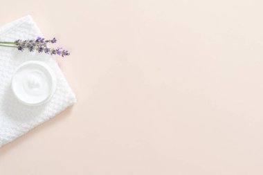 Nemlendirici vücut kremi, banyo havlusu, pastel pembe arka plan üzerinde lavanta çiçeği ile Kavanoz. Cilt bakımı kozmetik kavramı. Minimal düz döşeme stili kompozisyonu, üst görünüm, kopyalama alanı.