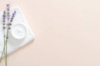 Nemlendirici vücut kremi, banyo havlusu, pastel pembe arka plan üzerinde lavanta çiçeği ile Kavanoz. Cilt bakımı kozmetik kavramı. Minimal düz döşeme stili kompozisyonu, üst görünüm, kopyalama alanı.