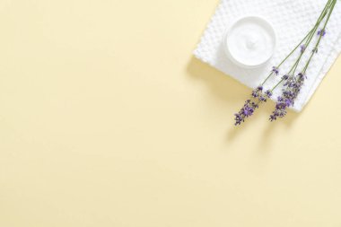 Nemlendirici vücut kremi, banyo havlusu, pastel sarı arka plan üzerinde lavanta çiçeği ile Kavanoz. Cilt bakımı kozmetik kavramı. Minimal düz döşeme stili kompozisyonu, üst görünüm, kopyalama alanı.