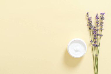 Pastel sarı arka plan üzerinde nemlendirici vücut kremi ve lavanta çiçeği ile Kavanoz. Cilt bakımı kozmetik kavramı. Minimal düz döşeme stili kompozisyon, üst görünüm, genel merkez.