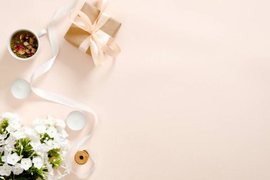 Hediye kutusu, çiçek buketi, kurdele, mumlar, pastel pembe arka plan üzerinde çay bardağı ile Flatlay kompozisyon. Düz döşeme, üst görünüm, kopyalama alanı. Aşk ve romantizm kavramı.