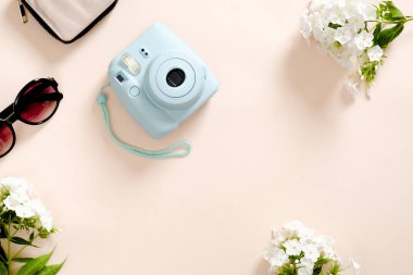 Modern kamera, güneş gözlüğü, pastel pembe renk arka plan üzerinde beyaz çiçekler. Üst görünüm, ihale minimal düz döşeme tarzı kompozisyon. Kadın masası, moda blogger, güzellik teknolojisi