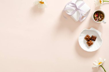 Hediye kutusu, bitkisel çay, kurdele, pastel pembe arka plan papatya papatya çiçek ile romantik flatlay kompozisyon. Kadınsı ev ofis masası konsepti. Düz döşeme, üst görünüm
