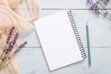 Boş kağıt not defteri, kalem, pastel pembe renkli battaniye, rustik mavi ahşap arka plan üzerinde lavanta çiçekleri. Üst görünüm, ihale minimal düz döşeme tarzı kompozisyon. Kadınsı şeyler ile Moda blogger masası