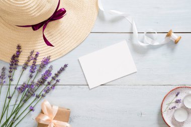 Hasır şapka, lavanta çiçekleri, kağıt kart maket, kurdele, hediye kutusu, mum ile Flatlay kompozisyon. Romantik aksesuarları ile kadınsı masa masa. Düz yatıyordu, üstten bak, tepede. Güzellik blogger çalışma alanı
