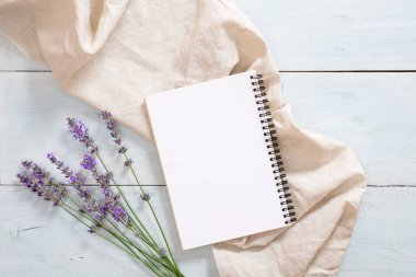 Boş kağıt not defteri, lavanta çiçeği, rustik mavi ahşap arka plan üzerine pastel bej battaniye ile Flatlay kompozisyon. Düz yatıyordu, üst görünüm natürmort kavramı.