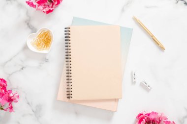 Boş kağıt defter, pembe çiçekler ve mermer arka plan üzerinde altın kırtasiye. Düz yatıyordu, üst görünüm modern ev ofis masası. Moda blogger çalışma alanı kavramı.
