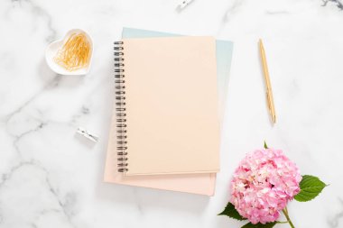 Boş kağıt defter, pembe ortanca çiçek ve mermer arka plan üzerinde altın kırtasiye. Düz yatıyordu, üst görünüm modern ev ofis masası. Moda blogger çalışma alanı kavramı.
