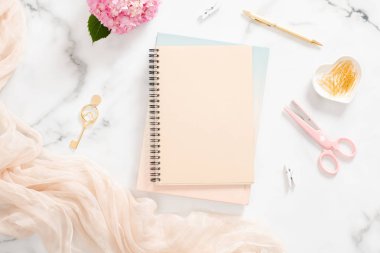 Boş kağıt defter, pembe ortanca çiçek, pastel battaniye ve mermer arka plan üzerinde şık aksesuarlar ile Flatlay ev ofis masası masa. Kadınsı arka plan, moda blogger çalışma alanı kavramı