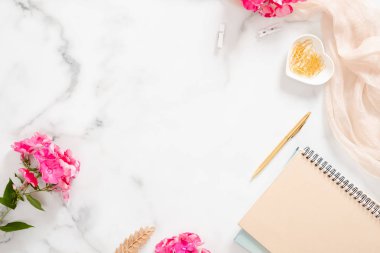 Flatlay ev ofis masası. Soluk pastel bej dizüstü bilgisayar, pembe çiçekler ve beyaz arka plan üzerinde süslemeleri ile çalışma alanı. Düz döşeme, üst görünüm.