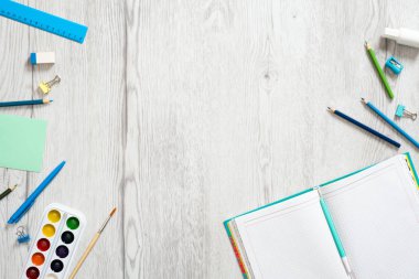 Okul defteri ve ahşap arka plan üzerinde çeşitli kırtasiye. Okul konseptine geri dönelim. Düz döşeme, üst görünüm, genel merkez.