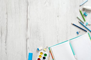 Okul defteri ve ahşap arka plan üzerinde çeşitli kırtasiye. Okul konseptine geri dönelim. Düz döşeme, üst görünüm, genel merkez.