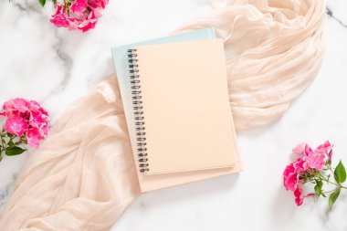 Mermer arka plan üzerinde boş kağıt defter, pembe çiçekler ve pastel battaniye ile Kompozisyon. Düz yatıyordu, üst görünüm natürmort kavramı.