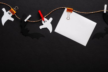 Hayaletler, yarasalar, siyah arka plan üzerinde klipler üzerinde boş kağıt kart ile Halloween kompozisyon. Cadılar Bayramı parti davetiye kartı mockup. Düz döşeme, üst görünüm, kopyalama alanı.