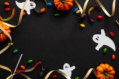 Kabaklar, hayaletler, şekerler, siyah arka plan üzerinde kurdele ile Halloween çerçeve. Cadılar Bayramı parti davetiye kartı mockup. Düz döşeme, üst görünüm, kopyalama alanı.