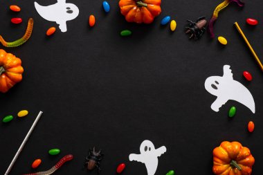 Kabaklar, hayaletler, şekerler, siyah arka plan üzerinde kurdele ile Halloween çerçeve. Cadılar Bayramı parti davetiye kartı mockup. Düz döşeme, üst görünüm, kopyalama alanı.