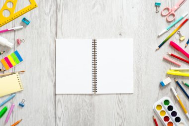 Geri okul konsepti, çeşitli okul malzemeleri ve ahşap arka plan üzerinde kopya alanı ile boş kağıt not defteri ile yaratıcı düzeni. Düz döşeme stili kompozisyon, üst görünüm, genel merkez.