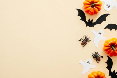 Cadılar Bayramı kompozisyonu. Cadılar Bayramı süslemeleri, kabaklar, hayaletler, kağıt yarasalar, pastel bej arka plan örümcekler. Cadılar Bayramı konsepti. Düz döşeme, üst görünüm, kopyalama alanı