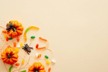 Metin için kopya alanı ile kabak ve şeker ile Modern Halloween arka plan. Pastel bej arka planda izole edilmiş. Düz yatıyordu, üstten bak, tepede. Cadılar Bayramı parti davetiye kartı mockup.