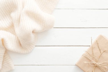 Sonbahar kompozisyonu. Ahşap beyaz arka plan üzerinde örme eşarp ve hediye kutusu ile kadınsı masa masa. Düz yatıyordu, üstten bak. İskandinav, hygge, rahat ev konsepti