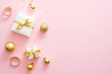 Noel kompozisyonu. Kopya alanı ile pastel pembe arka plan Noel altın süslemeleri. Düz döşeme, üst görünüm