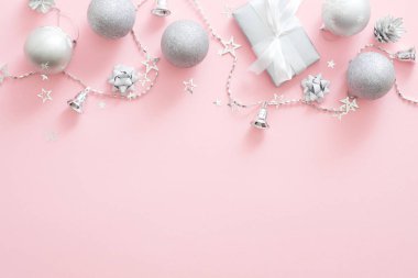 Noel süslemeleri, şık gümüş hediye kutusu, topları, konileri, kurdele, pastel pembe arka plan konfeti. Minimal düz döşeme stili kompozisyon, üst görünüm, kopyalama alanı. Noel moda glamour kavramı.