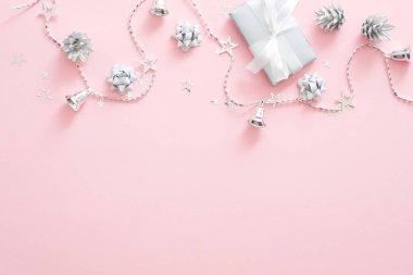 Noel süslemeleri, şık gümüş hediye kutusu, çam kozalağı, kurdele, pastel pembe arka plan konfeti. Minimal düz döşeme stili kompozisyon, üst görünüm, kopyalama alanı. Noel moda glamour kavramı