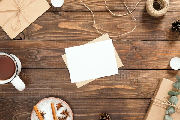 Mektup, boş kağıt kart, çay fincan, hediye kutusu, tarçın çubukları, zarf, ip, ahşap arka plan üzerinde mumlar ile Sonbahar flatlay kompozisyon. Rahat sonbahar veya kış tatili konsepti. Düz döşeme, üst görünüm