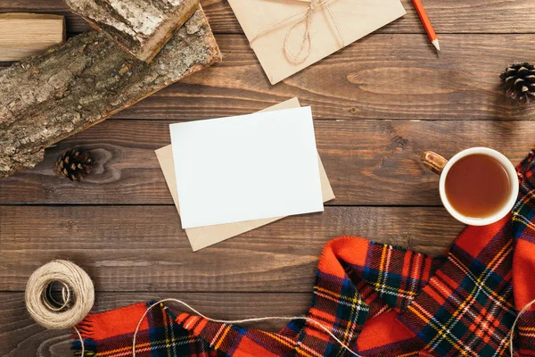 Hygge tarzı sonbahar flatlay kompozisyon mektup, boş kağıt kartı, moda kadınsı kırmızı eşarp, ip, zarf, ahşap arka plan üzerinde yakacak odun. Düz yatıyordu, üstten bak, tepede. Rahat ev çalışma alanı,