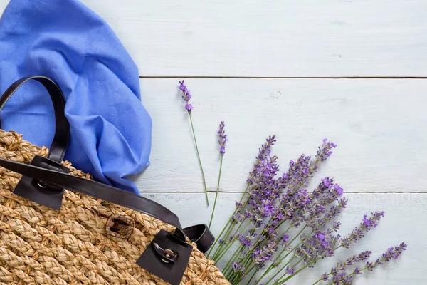 Bolso de verano para mujer con flores de lavanda y bufanda azul sobre fondo de madera color pastel. Acostado plano, vista superior, arriba. Concepto de moda de verano . — Foto de Stock