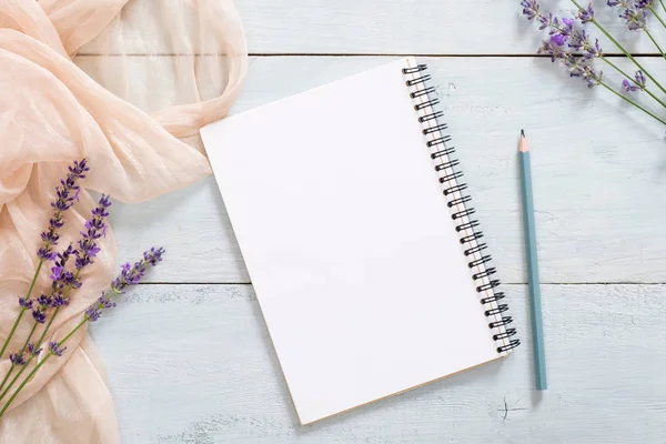Boş kağıt not defteri, kalem, pastel pembe renkli battaniye, rustik mavi ahşap arka plan üzerinde lavanta çiçekleri. Üst görünüm, ihale minimal düz döşeme tarzı kompozisyon. Kadınsı şeyler ile Moda blogger masası
