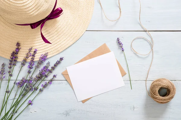 Vintage zarf, boş kağıt kart mockup, lavanta çiçekleri, hasır şapka ve rustik mavi ahşap arka plan üzerinde ip. Romantik kompozisyon, aşk mektubu kavramı. Düz döşeme, üst görünüm, genel merkez.