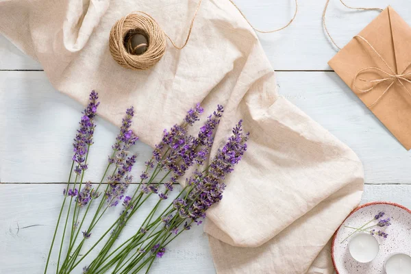 Flatlay lavanta çiçekleri, pastel bej battaniye, ip, rustik mavi ahşap arka plan üzerinde mumlar. Kadınsı masa. Düz yatıyordu, üstten bak, tepede. Yaz moda konsepti
