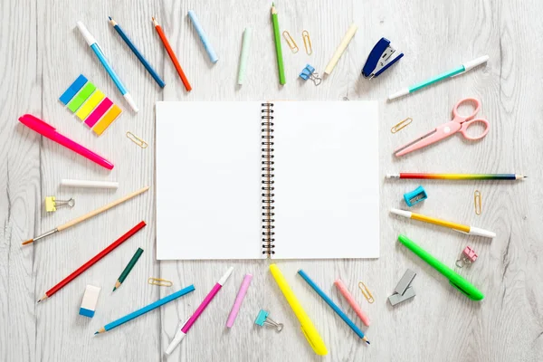 Geri okul konsepti, çeşitli okul malzemeleri ve ahşap arka plan üzerinde kopya alanı ile boş kağıt not defteri ile yaratıcı düzeni. Düz döşeme stili kompozisyon, üst görünüm, genel merkez.
