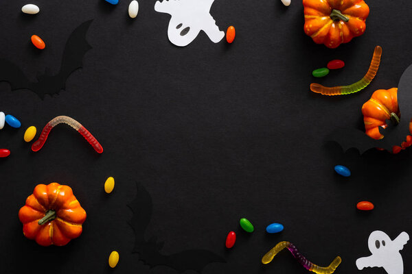 Halloween frame with pumpkins, candy, ghosts isolated on black background. Halloween party invitation card mockup. Flat lay, top view, copy space.