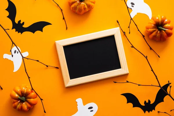 Mutlu cadılar bayramı konsepti. Cadılar Bayramı süslemeleri, resim çerçevesi, balkabağı, yarasalar, turuncu arka plandaki hayaletler. Kopya alanı ile Cadılar Bayramı parti tebrik kartı mockup. Düz döşeme, üst görünüm, genel merkez.