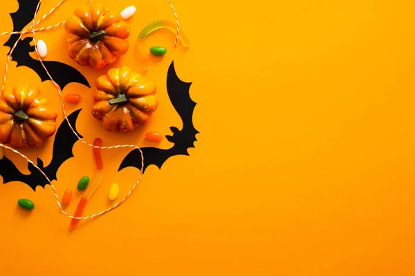 Happy halloween holiday concept. Halloween decorations, pumpkins, bats, candy, ghosts, bugs on orange background. Halloween party greeting card mockup with copy space. Flat lay, top view, overhead.