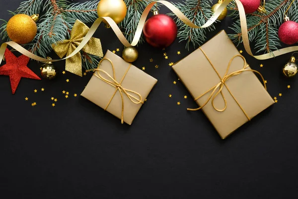 Noel kompozisyonu. Kırmızı ve altın Noel süslemeleri, süs eşyaları, köknar ağacı dalları, kopya alanı ile koyu siyah arka plan üzerinde hediyeler. Banner maket, kartpostal. Düz döşeme, üst görünüm, genel merkez