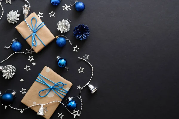 青いリボン、青いボール、モミの木の枝、コーン、コピースペースと暗い黒の背景に紙吹雪とクリスマスプレゼント。フラットレイ、トップビュー、オーバーヘッド。クリスマス休暇、新年バナーモックアップ. — ストック写真