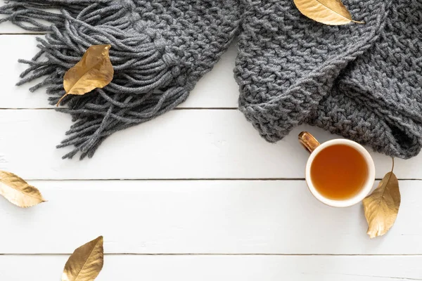 Composizione autunnale. Tavolo da scrivania femminile con sciarpa lavorata a maglia, tazza di tè, foglie autunnali su sfondo bianco in legno. Posa piatta, vista dall'alto. Nordic, hygge, accogliente concetto di casa — Foto Stock