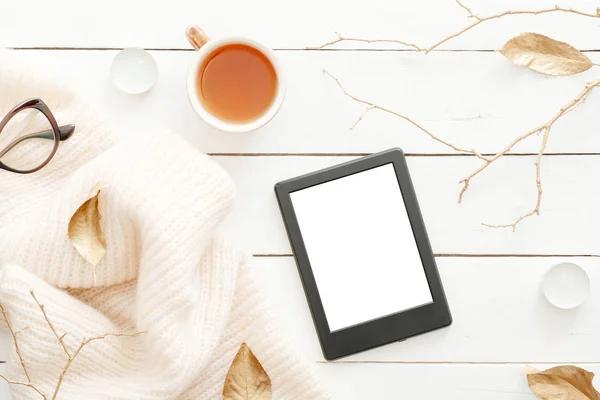 Örgü ekose, çay bardağı, sonbahar yaprakları, ahşap beyaz arka plan üzerinde boş ekran ile tablet ile rahat ev masası masa. Üst görünüm, düz döşeme, kopyalama alanı. Sonbahar kompozisyonu. İskandinav hygge tarzı kavramı.
