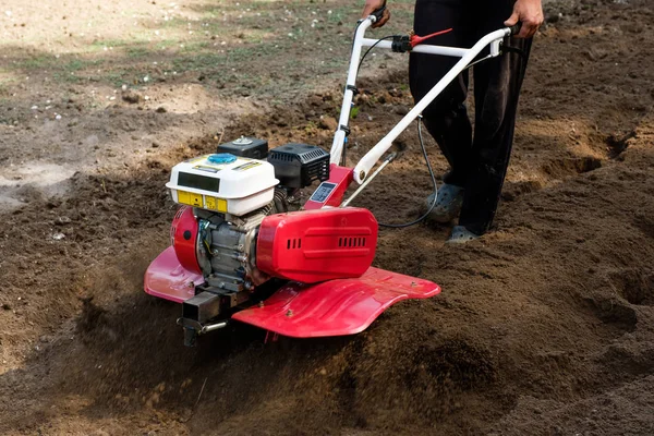 Homme travaillant dans le jardin avec une machine à tiller de jardin. Chariot de jardin pour travailler, gros plan — Photo